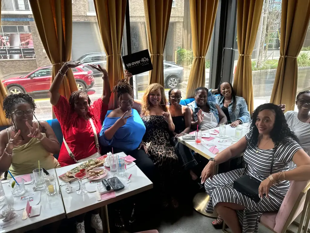 Black women over 40 in Atlanta laughing and dining together at a Us Over 40s Friends Group event